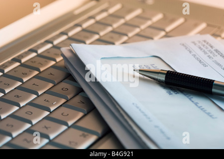 A laptop keyboard with a stack of bills and a pen on it Stock Photo