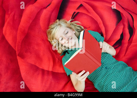 A girl lying on a blanket and reading a book Stock Photo