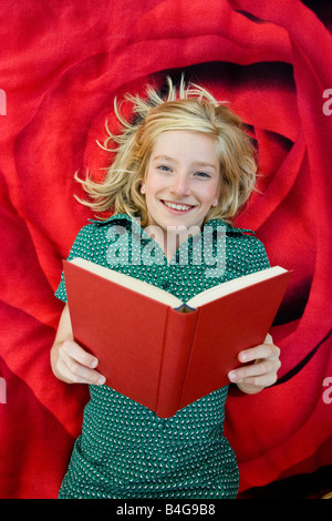 A girl lying on a blanket and reading a book Stock Photo