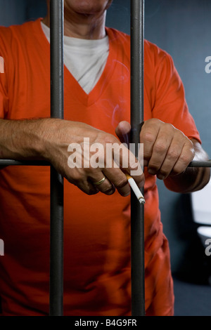 A prisoner smoking a cigarette in his prison cell Stock Photo