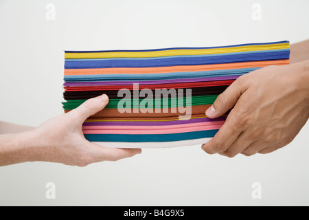 Human hands exchanging stack of multi colored paper Stock Photo