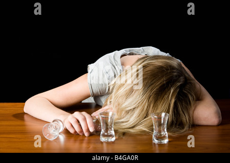 A young woman passed out drunk on a bar counter Stock Photo
