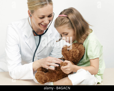 Female pediatrician examining a girl's teddy bear Stock Photo