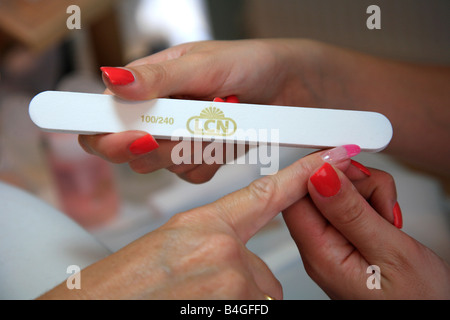 Manicure filing a Ladys Nails with a Nailfile in a Trendy High Street Beauty Parlour Salon Stock Photo