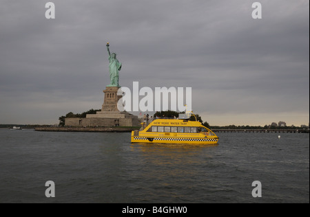 A New York Water Taxi, which provides ferry service between Manhattan, Brooklyn and New Jersey, passes the Statue of LIberty. Stock Photo