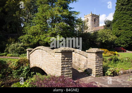 Bridge in Coronation gardens in the village of Waddington Lancashire with St Helens Church in background Stock Photo