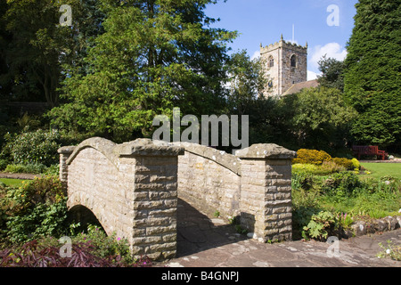 Bridge in Coronation gardens in the village of Waddington Lancashire with St Helens Church in the background Stock Photo