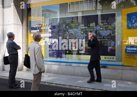 Japanese business man views a bank stocks and shares monitor screen showing the latest values of commodities Tokyo Japan Stock Photo