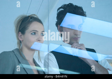 Businessman and businesswoman looking through window Stock Photo