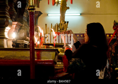 Woman lighting candle in Buddhist temple Stock Photo