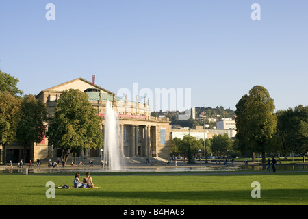 Two women sitting on grass in front of theater Stuttgart Staatstheater Stuttgart Baden-Wurttemberg Germany Stock Photo