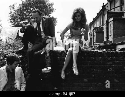 Film Bedazzled 1967 Raquel Welch with Peter Cook and Dudley Moore Peter Cook gets a good view up Raquel Welch s skirt as they take a break from filming to have a bite to eat Stock Photo