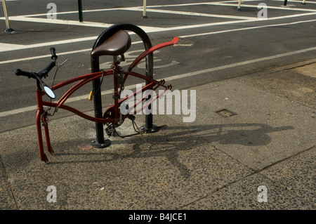 An abandoned red bike with its wheels missing in the New York neighborhood of Chelsea Stock Photo