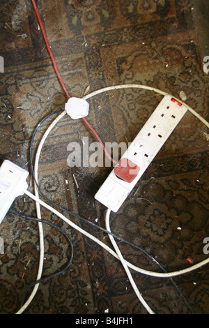 electricity plugs and extension lead dirty carpet Stock Photo