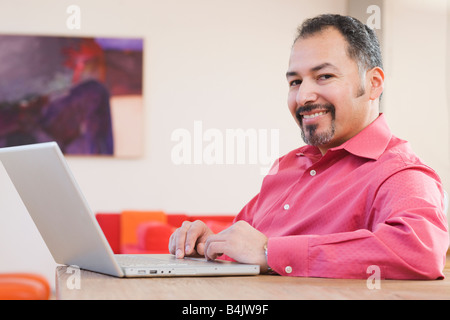 Hispanic man typing on laptop Stock Photo