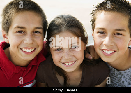 Hispanic twin brothers and sister hugging Stock Photo