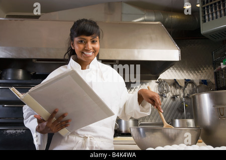Mixed Race female baker mixing batter Stock Photo