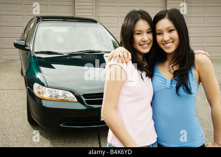 Asian sisters hugging in driveway Stock Photo