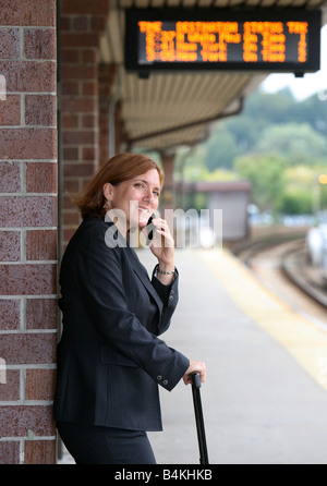 Commuting businesswoman keeps busy while awaiting the arrival of her train Stock Photo