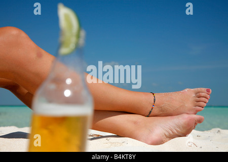 Woman's feet with a Mexican style beer in the foreground Stock Photo