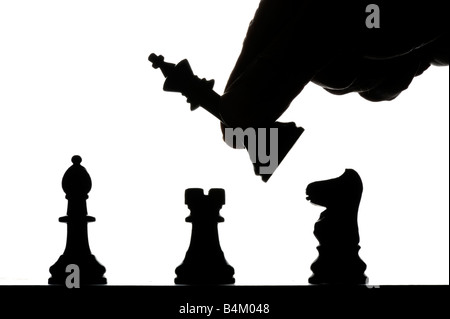 male hand moving chess pieces silhouetted on chess board Stock Photo
