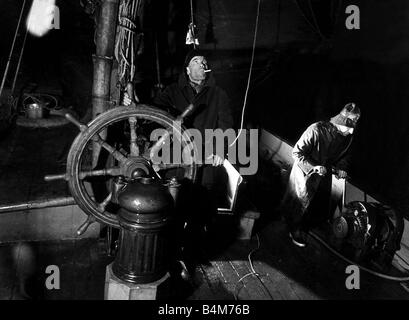 Skipper Harry Evans at the wheel of the Thames sailing barge Ardwina as she rounds Beachy Head in the English Channel as the first mate mans the pump April 1936 Stock Photo