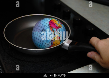A globe is shown being fried in a skillet on a stove burner representing the concept of Global Warming Stock Photo