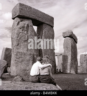 One of Britain s most famous and mysterious ancient monuments Stonehenge on Salisbury Plain Wiltshire a young couple look at the monument where Druid pilgrims come to worship during the Summer Solstice Stock Photo