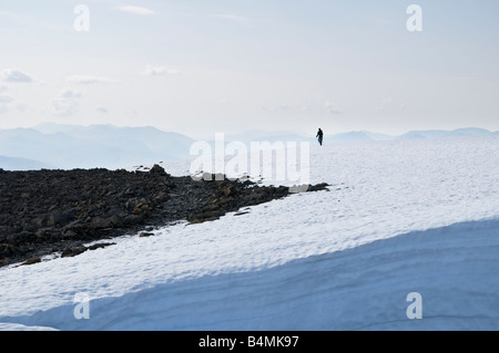 Single female hiker walking on snow covered summit of Ben Nevis in late spring, Lochaber, Scotland Stock Photo