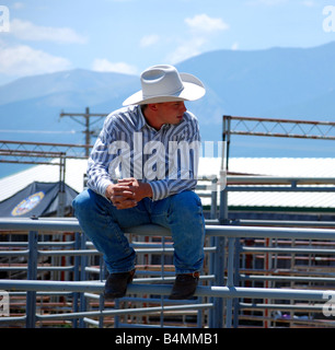 Rodeo cowboy sitting on the rails of a pen Stock Photo