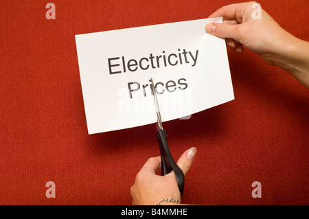 Picture of person cutting a piece of paper with 'Electricity prices' written on it using a pair of scissors Stock Photo