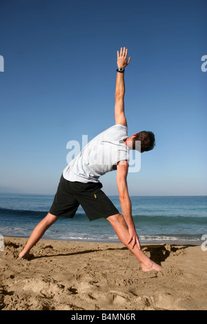Man doing yoga exercise on the beach Stock Photo