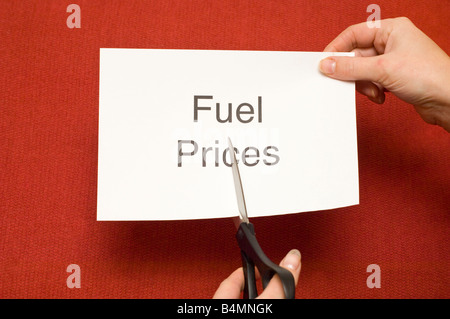 Picture of person cutting a piece of paper with 'Fuel prices' written on it using a pair of scissors Stock Photo