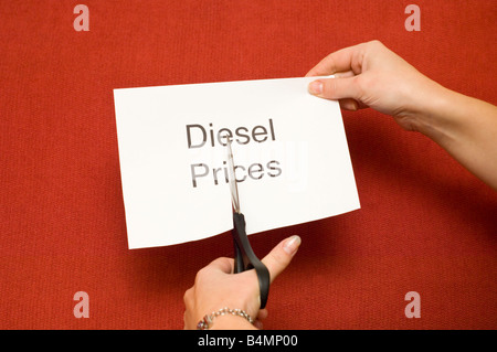 Picture of person cutting a piece of paper with 'Diesel prices' written on it using a pair of scissors Stock Photo