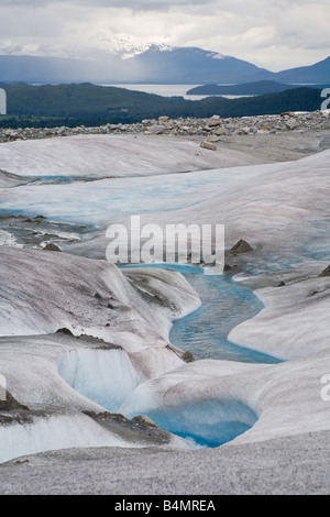 Streams of deep blue water form interesting patterns while running on surface of Mendenhall Glacier in Alaska Stock Photo