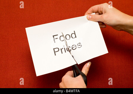 Picture of person cutting a piece of paper with 'Food prices' written on it using a pair of scissors Stock Photo