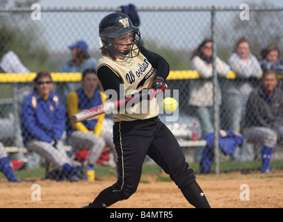 A high school softball player hits the ball during a game Stock Photo