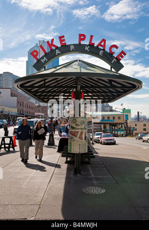 Couple walking in downtown Seattle Washington under bus stop shelter advertising nearby Pike Place Market Stock Photo