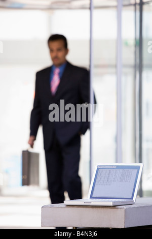 Businessman outdoors in front of building using laptop with businessman in background (high key/selective focus) Stock Photo