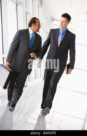 Two businessmen walking in a corridor talking (high key/selective focus) Stock Photo