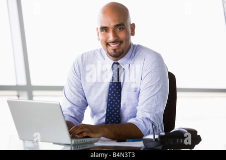 Businessman in office with laptop smiling (high key/selective focus) Stock Photo