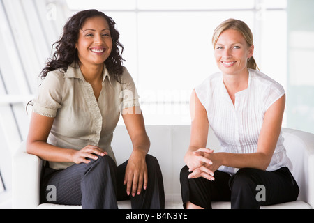 Two businesswomen sitting indoors smiling (high key/selective focus) Stock Photo