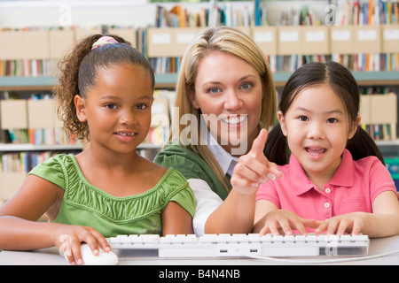 Two students in class at computer keyboard with teacher Stock Photo