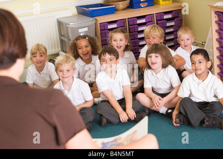 Students in class sitting on floor with teacher in foreground (selective focus) Stock Photo
