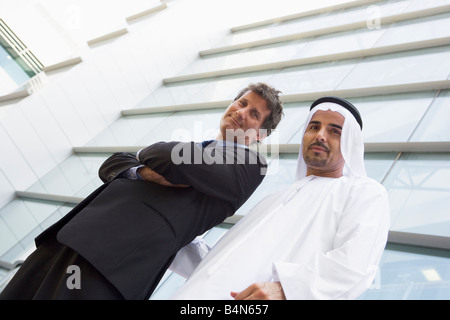 Two businessman standing outdoors by building smiling (high key/selective focus) Stock Photo