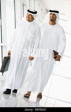 Two businessmen walking in corridor smiling (high key/selective focus) Stock Photo