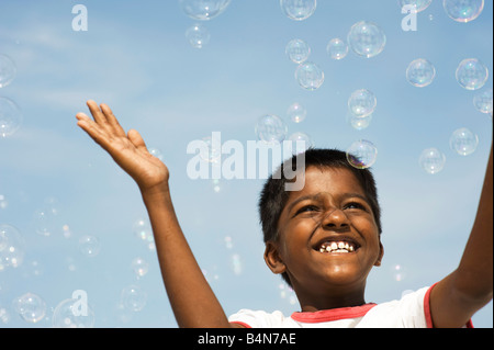 Indian boy playing with bubbles against blue sky. Andhra Pradesh, India Stock Photo