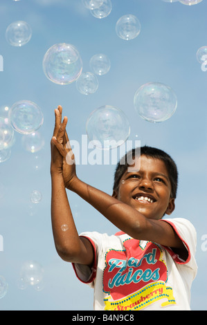 Indian boy playing with bubbles against blue sky. Andhra Pradesh, India Stock Photo