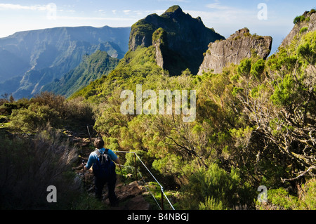 Walker descends from Pico da Encumeada Madeira with the plateau of Paul do Serra beyond Stock Photo