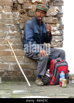 A Chinese native smoking in a Chairman Mao cap on the Great Wall of China Stock Photo